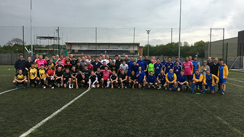 The charity football team posing in football kit with the Loughborough University Stadium in the background.